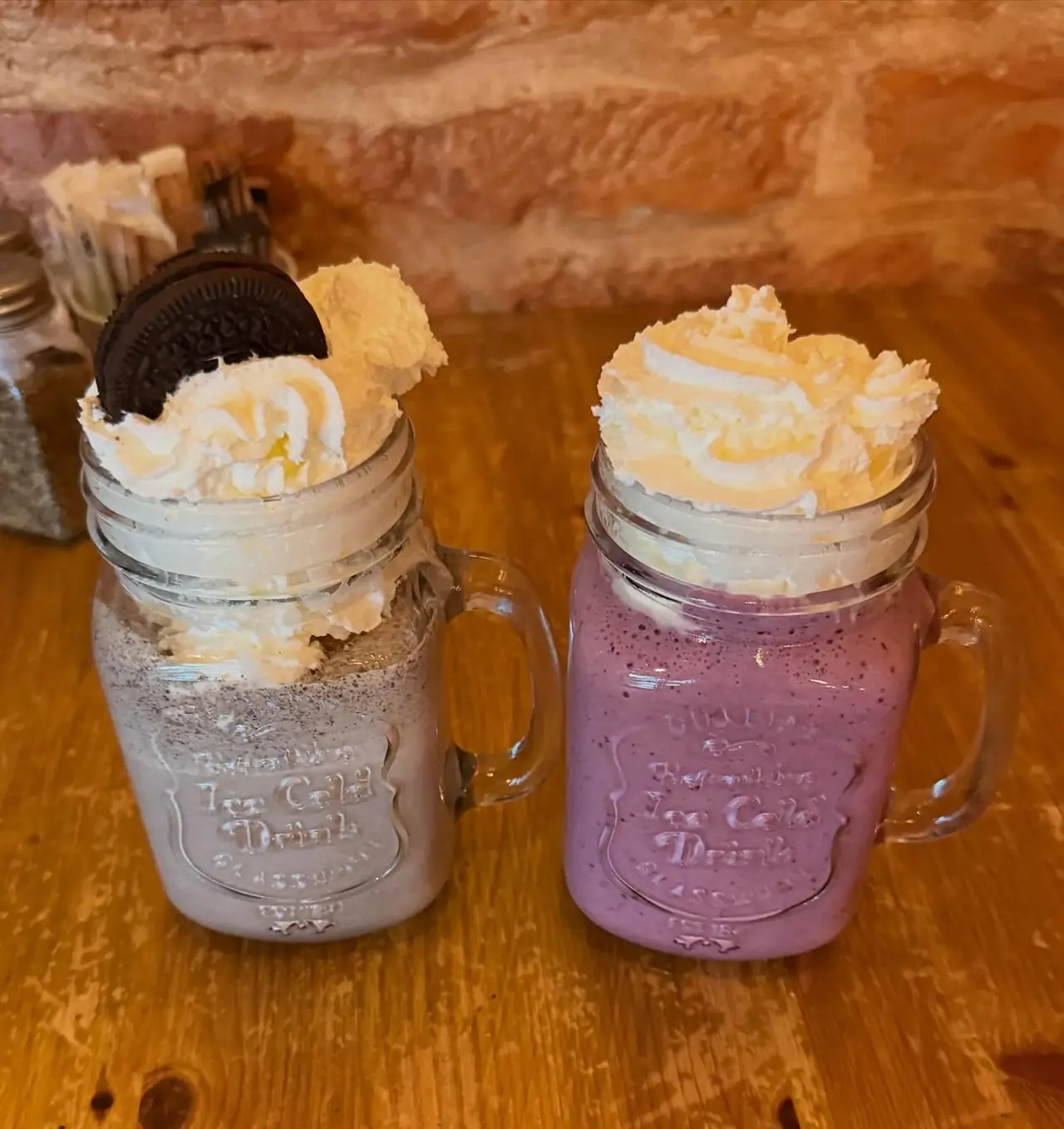 Two milkshakes topped with cream